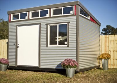 10x12 Modern Building Galvalume with Dark Gray Trim and Red Smart Board Transition. 4’ Door and 3’x3’ Double Pane Window